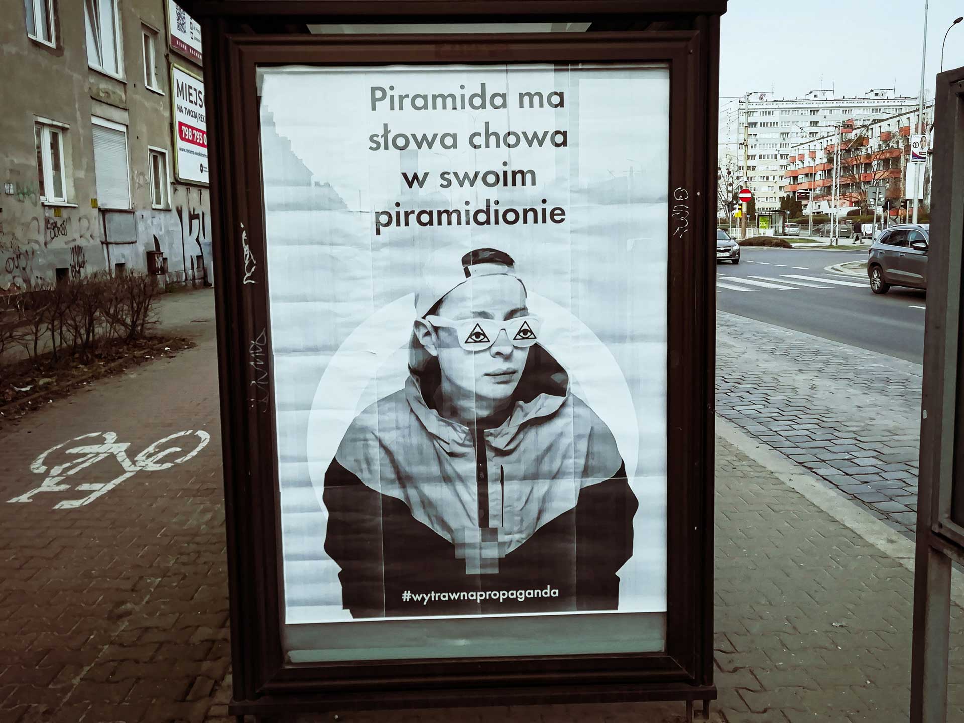 Plakat na przystanku z napisem: piramida ma, słowa chowa, w moim piramidionie 